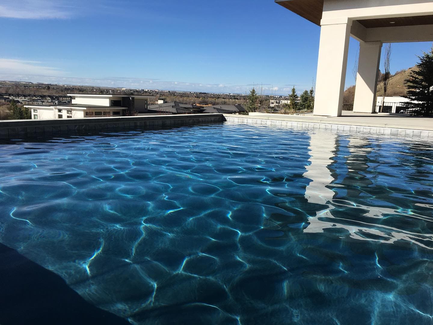 A shallow pool/spa with a large pool in the background